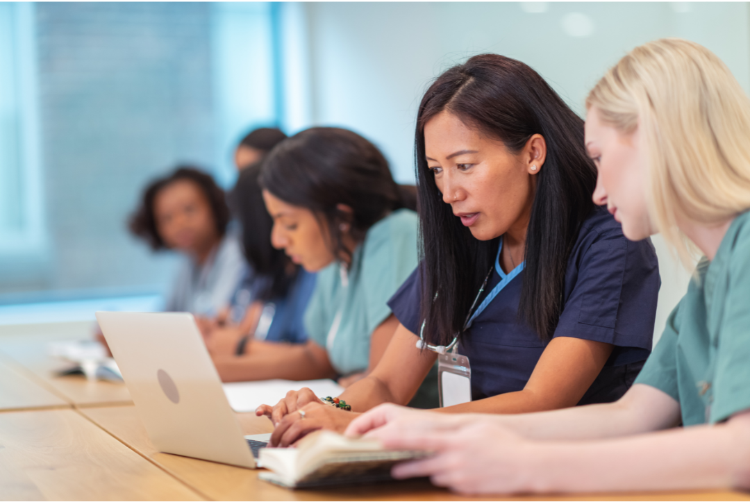Nursing students in scrubs working on a computer
